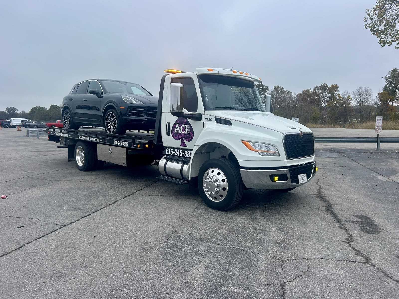 ace towing tow truck with black car on bed