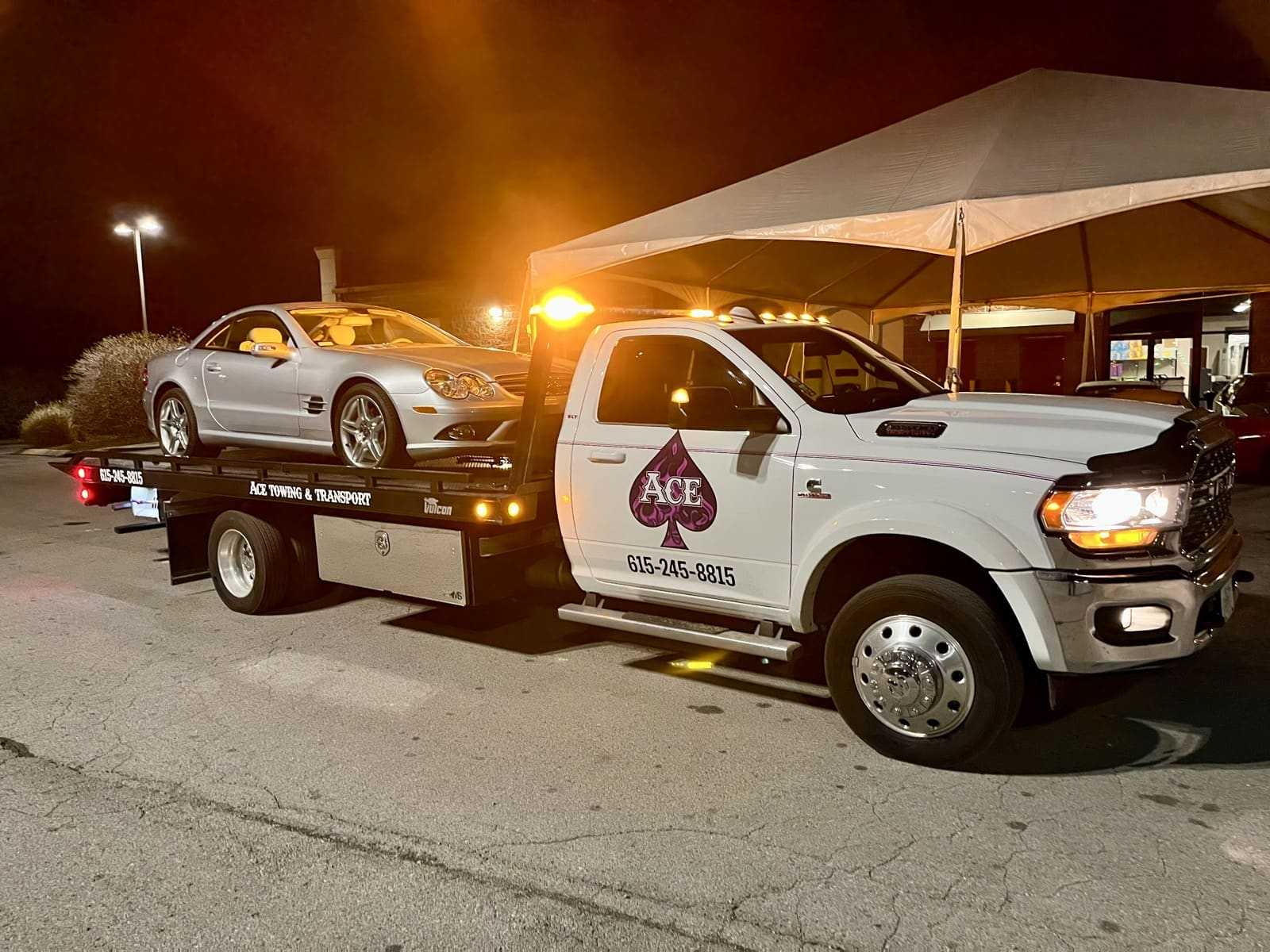 ace towing tow truck with silver car on bed