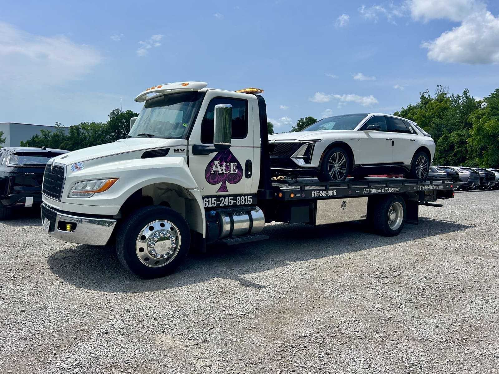 ace towing tow tuck with white car on bed in parking lot